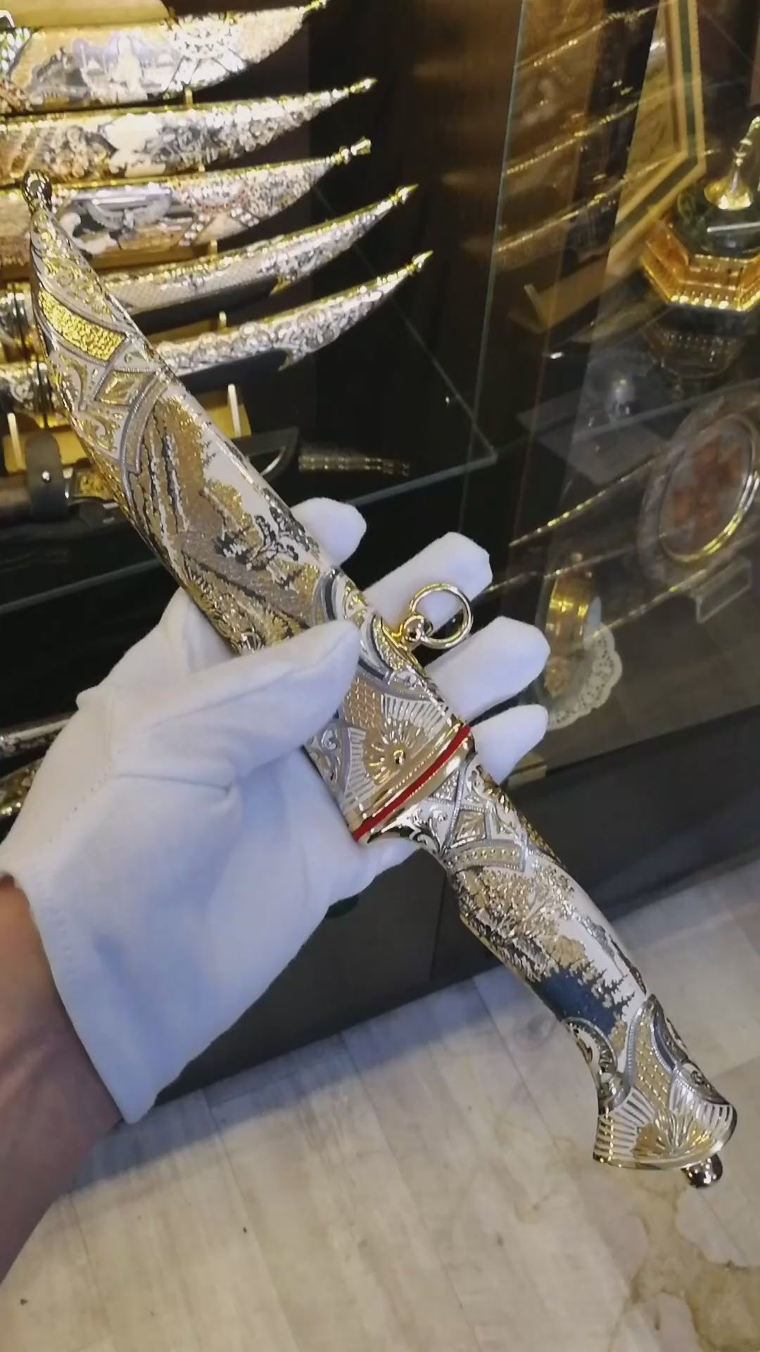 Un cuțit lucrat manual cu lamă de oțel cu model, incrustații aurii, mâner de vultur sculptat și teacă decorativă cu tematică de șoim.
